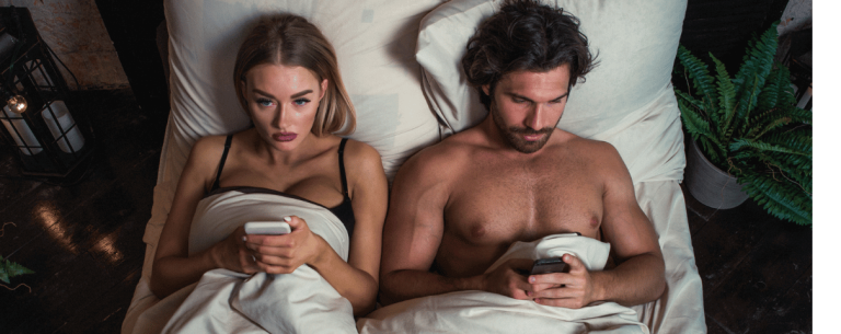 Para leży w łóżku z telefonem w ręku