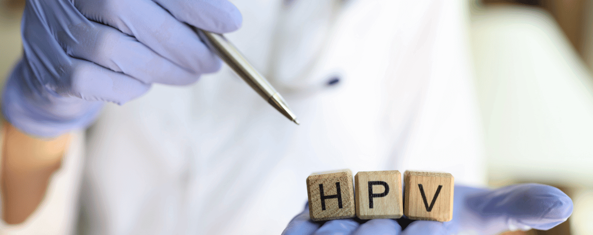 Lekarz w gumowych rękawiczkach wskazuje na kostki z napisem HPV